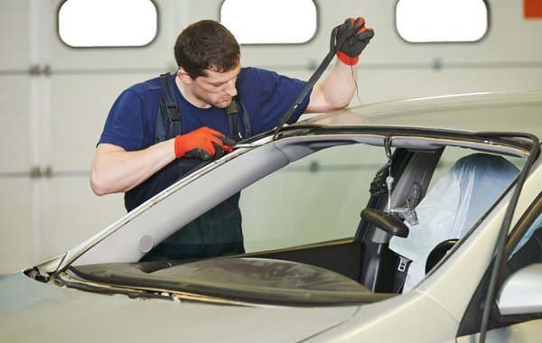 Technician removing a windshield seal during auto glass service