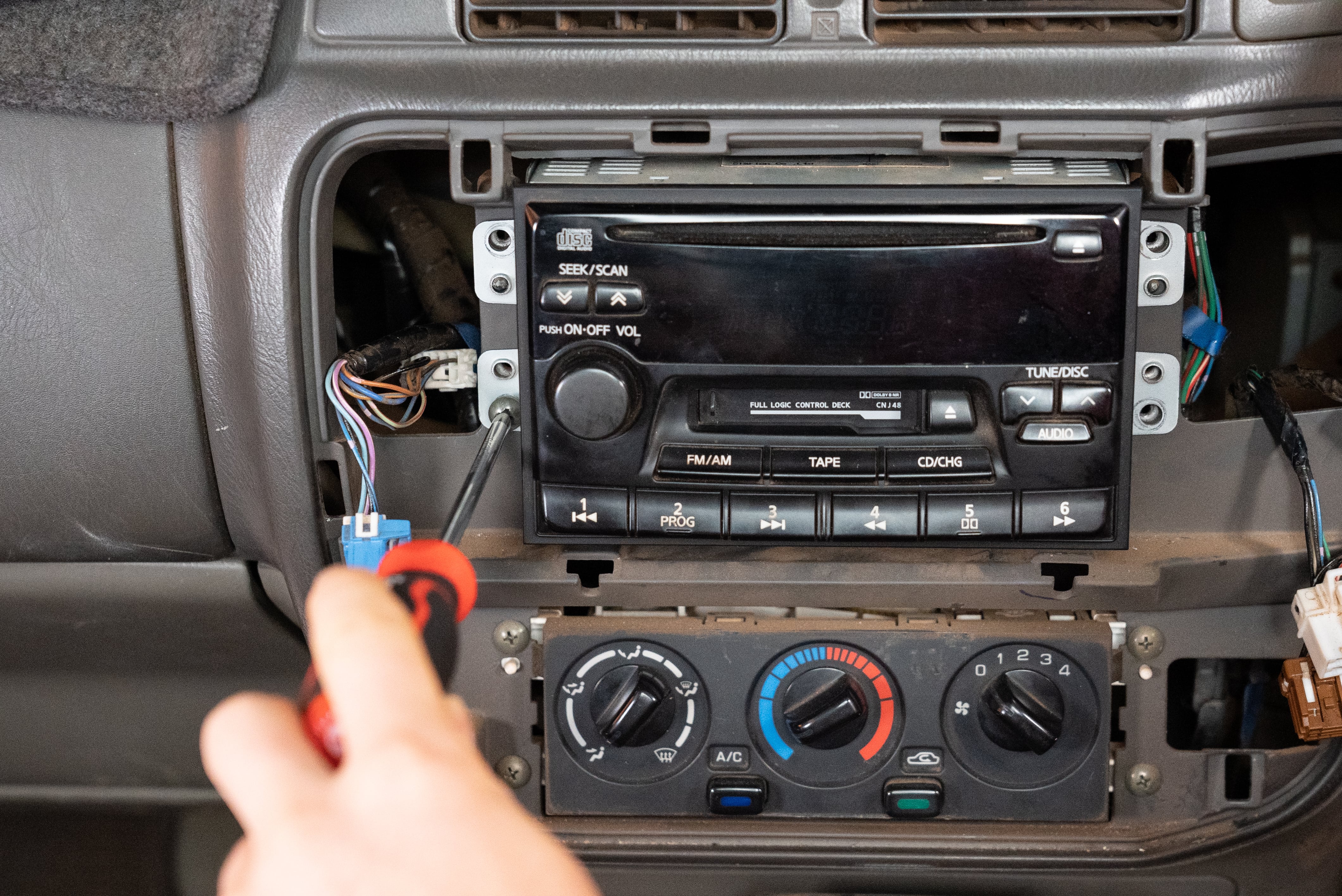 Technician removing a factory stereo from a dashboard