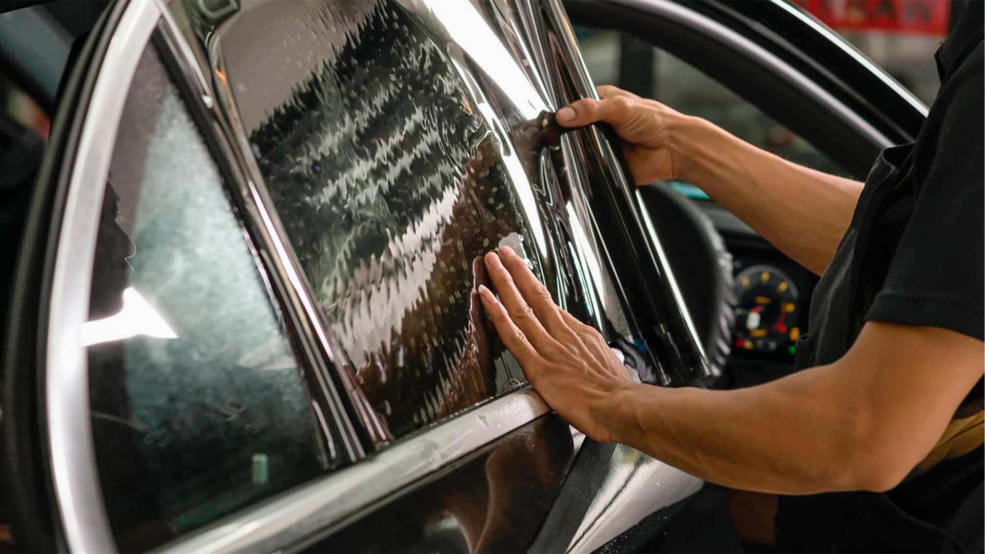Technician installing window tint film on a car window