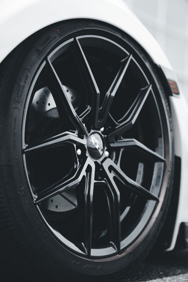 Black custom alloy wheel fitted on a white sports car