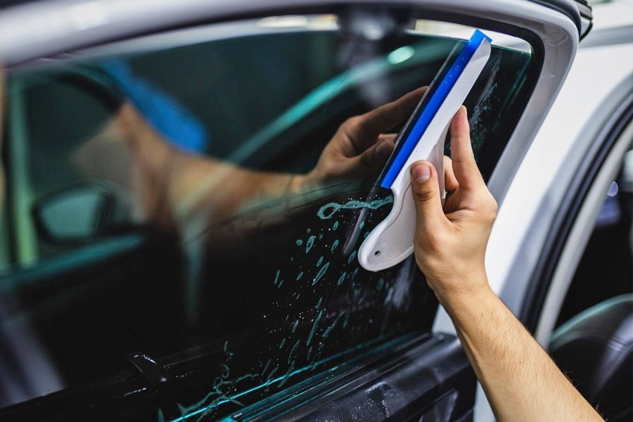 Close-up of a squeegee smoothing tint film onto a car window