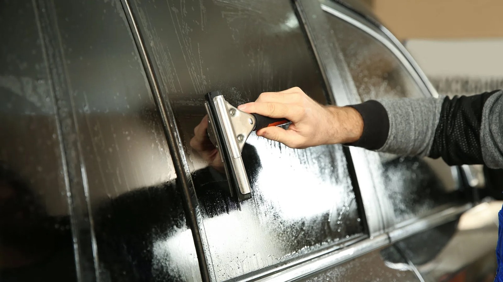 Installer smoothing tint film across a car window with a squeegee