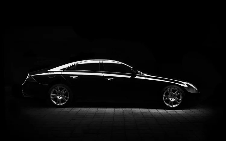 Black sedan with dark tinted windows photographed in dramatic low light