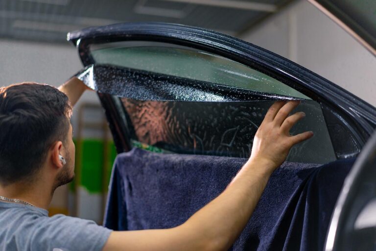 Technician applying window tint film to a car window
